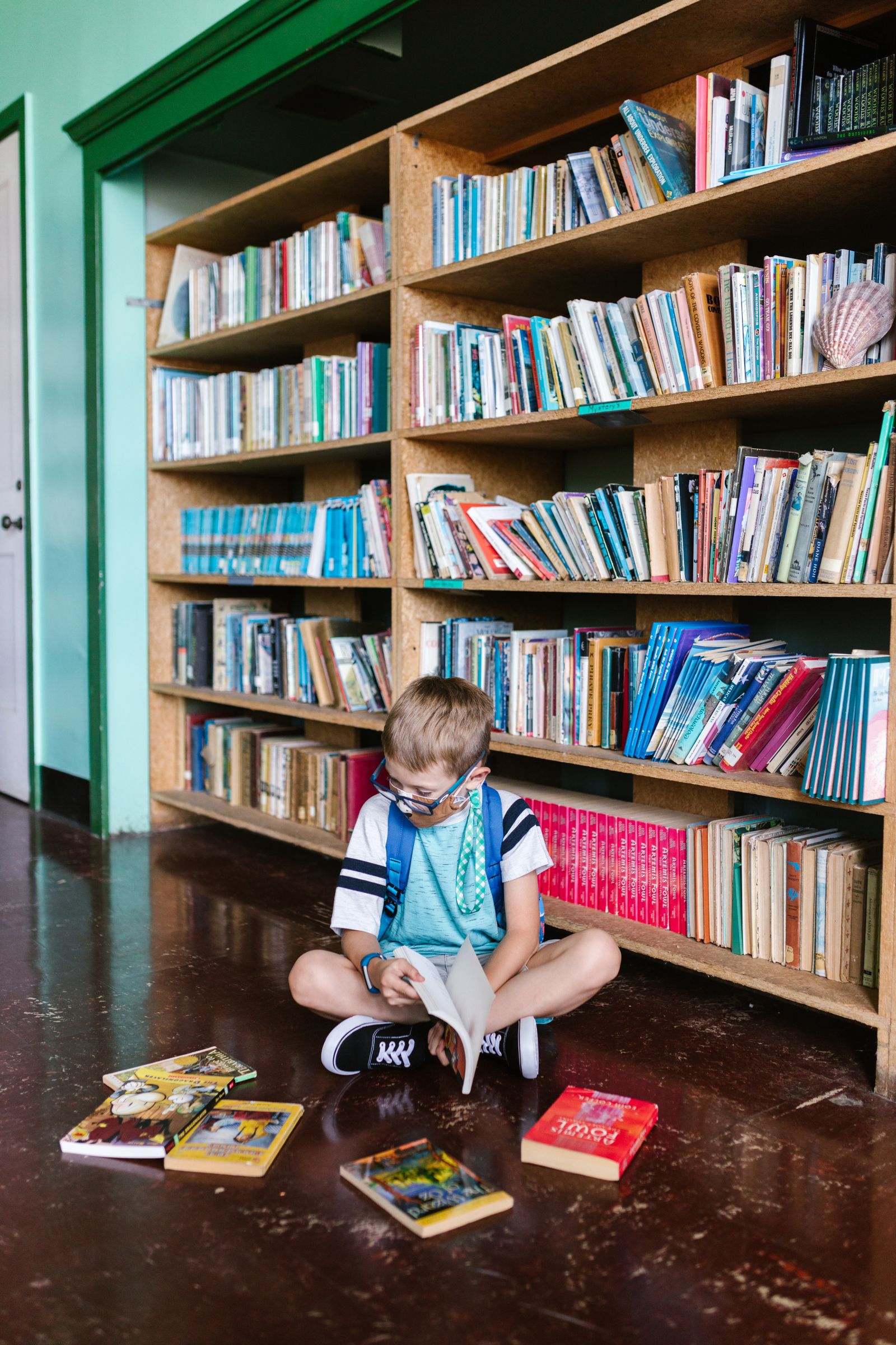 Two children reading books together in the library